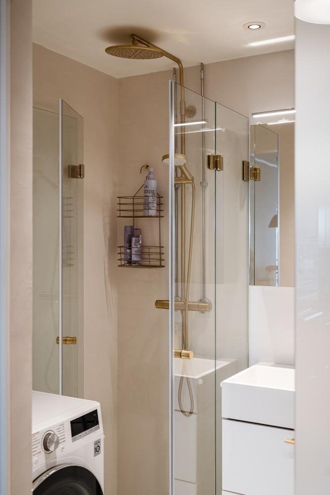 Beige saumaton suihkutila, kultaiset hanat ja pyykinpesukone Turussa